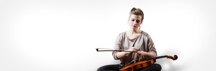 young woman applies rosin to a bow